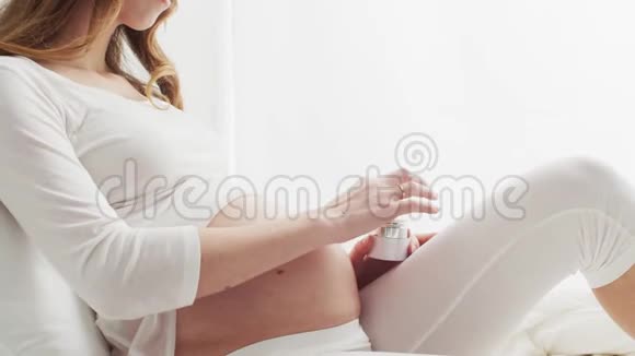 快乐的孕妇在她美丽的腹部涂上奶油怀孕母性和期望概念视频的预览图