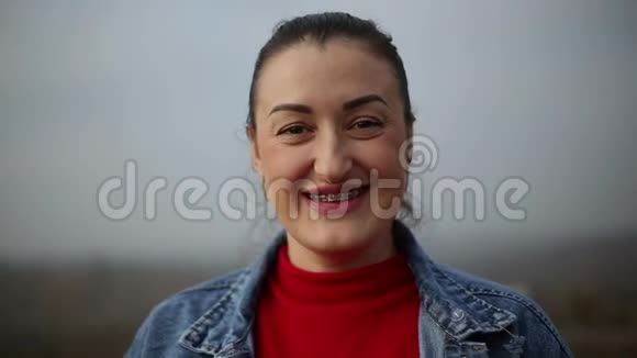 微笑的女人的肖像戴着牙套穿着红色毛衣和牛仔裤夹克视频的预览图