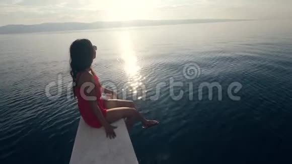 一个穿着红色连衣裙和太阳镜坐在船边的女孩视频的预览图