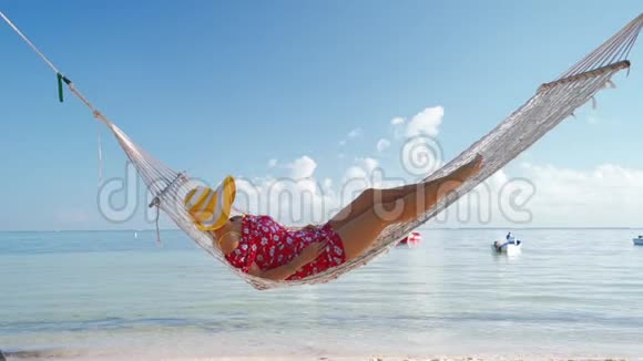 女孩在热带岛屿海滩的吊床上放松多米尼加共和国蓬塔卡纳的暑假视频的预览图
