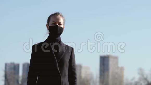 穿着黑色防护面具和黑色太阳镜的年轻女孩在街上视频的预览图