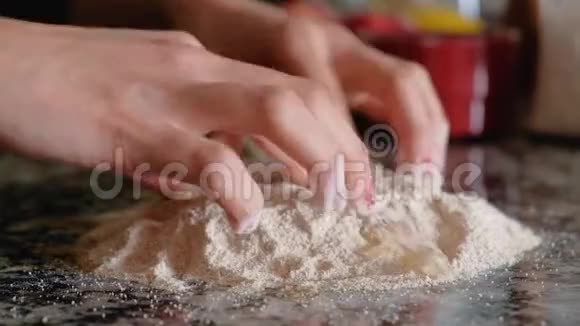 女人把一个鸡蛋和整个小麦粉混合在台面上视频的预览图