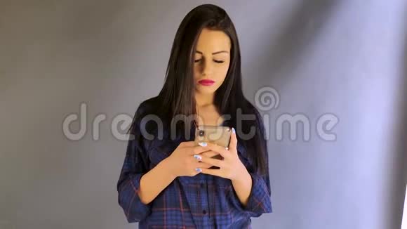 美丽的年轻女孩黑发在电话里发短信微笑着视频的预览图