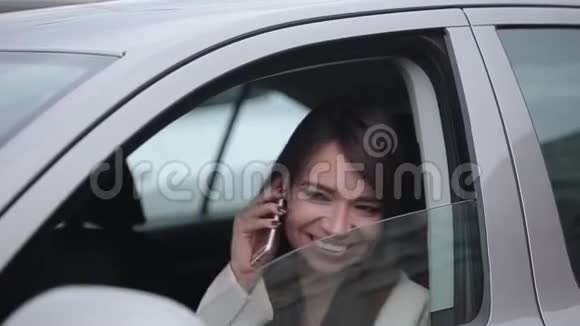 漂亮的商务女性正在手机上说话坐在车里微笑视频的预览图
