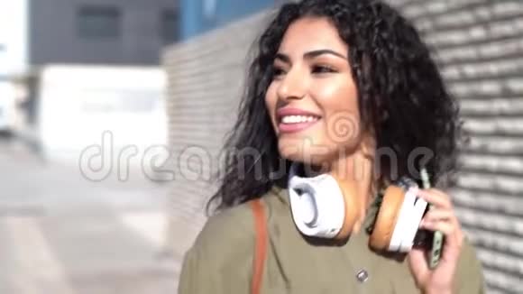 带着耳机走在街上的年轻阿拉伯女人视频的预览图