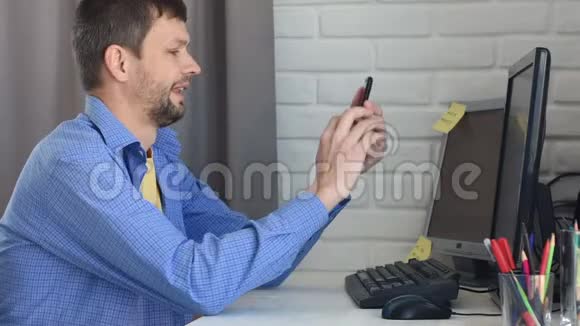 一个男人坐在桌子旁通过电话进行视频交流视频的预览图