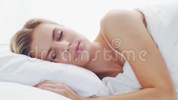 躺在床上的年轻女子美丽的金发女郎早上在卧室健康和休息的理念视频的预览图