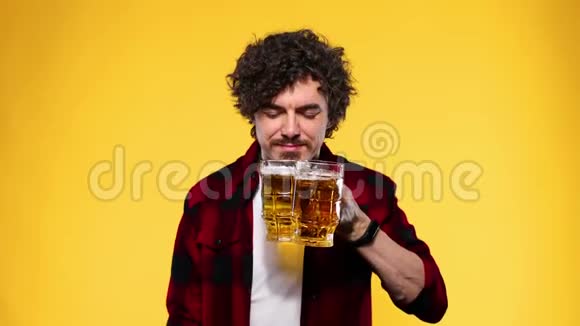 圣帕特里克节年轻的啤酒节男子提供大啤酒杯与饮料隔离在黄色背景一个男人视频的预览图