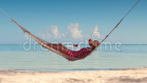 女孩在热带岛屿海滩的吊床上放松多米尼加共和国蓬塔卡纳的暑假视频的预览图