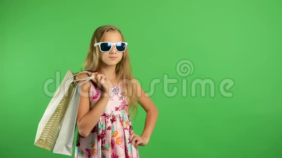女孩拿着五颜六色的手提包微笑地走在绿色的屏幕上购物愉快视频的预览图