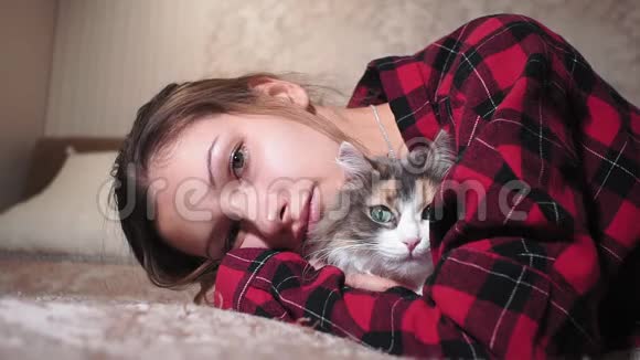 年轻女孩画像带着宠物一只猫躺在沙发上抚摸着猫视频的预览图