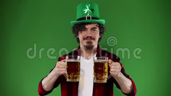 圣帕特里克节年轻的啤酒节男子提供大啤酒杯与饮料隔离在绿色背景动作缓慢视频的预览图