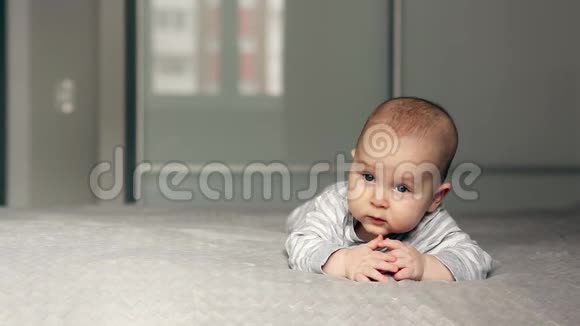 一个漂亮的小宝宝躺在床上看着摄像机视频的预览图