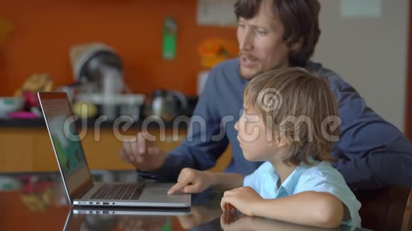 一个年轻人和他的小儿子在隔离期间坐在家里并在互联网学校使用平板电脑学习科罗纳视频的预览图