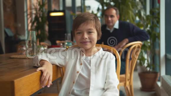 小男孩坐在咖啡馆里微笑视频的预览图
