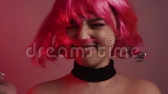 粉红色短发的女孩长粉色耳环和化妆的模特视频中的女孩笑调情摆姿势跳舞视频的预览图