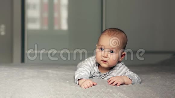 一个漂亮的小宝宝躺在床上看着摄像机视频的预览图