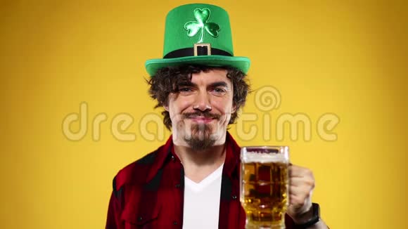 圣帕特里克节年轻的啤酒节男子提供大啤酒杯与饮料隔离在黄色背景视频的预览图
