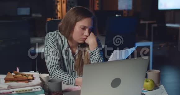 年轻的女经理看着疲惫的工作睡在手边累了的女上班族一边看文件视频的预览图
