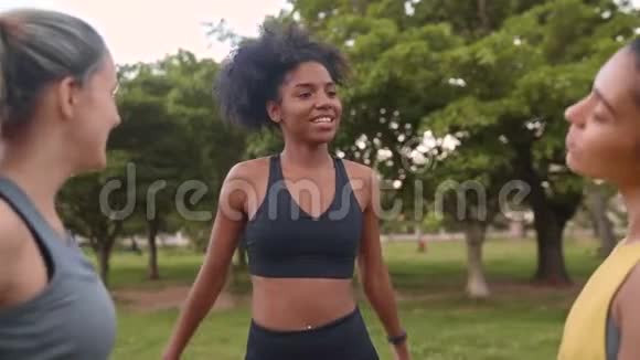 三位不同身材的女性朋友穿着运动服在公园锻炼前做伸展运动朋友视频的预览图