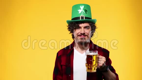 圣帕特里克节年轻的啤酒节男子提供大啤酒杯与饮料隔离在黄色背景一个男人视频的预览图