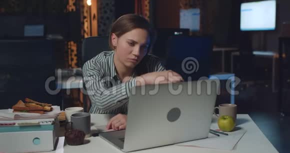 疲惫的女办公室工作人员关闭她的笔记本电脑和砰的头在手臂上女商人看起来很疲惫视频的预览图