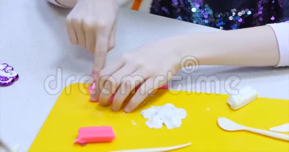 年轻的女孩子或女艺术家在一个艺术讲习班在一张桌子上坐下从塑料上剪下来程序视频的预览图