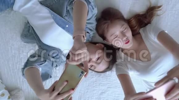 两个漂亮的亚洲朋友正在床上玩手机消费技术的概念正在一个视频的预览图