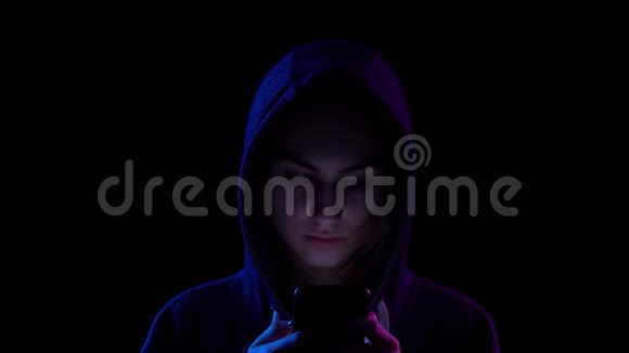 一个戴着兜帽的年轻女人手里拿着手机特写黑客通过电话攻击蓝色和红光视频的预览图