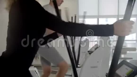 穿着运动服的男人和女人在现代健身房骑运动自行车训练腿视频的预览图