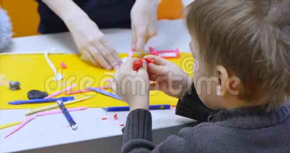 年轻的男儿童或男艺术家在一个艺术工作室坐在一张桌子上用橡皮泥雕刻学习过程视频的预览图