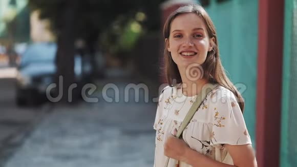 年轻美丽的快乐女孩的肖像棕色头发蓝眼睛雀斑穿着白色的花裙和包视频的预览图