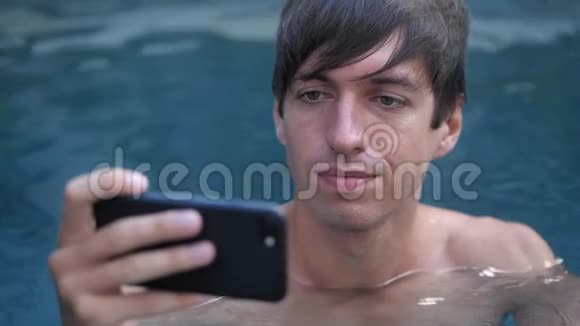 惊恐的男人在游泳池里放松时对他在智能手机上看到的东西感到不愉快的震惊视频的预览图