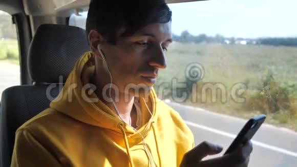 男子旅行者乘坐公共汽车持有智能手机和听音乐耳机视频的预览图