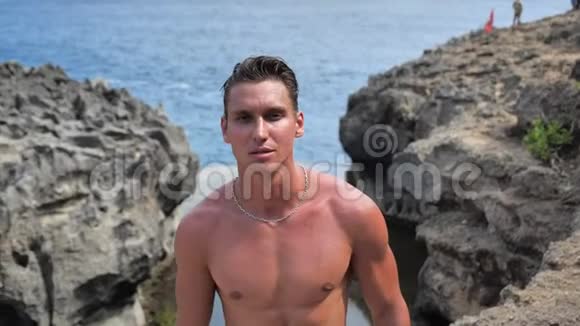 夏天的下午一个英俊的肌肉男模特在海滩上以大海为背景摆姿势视频的预览图