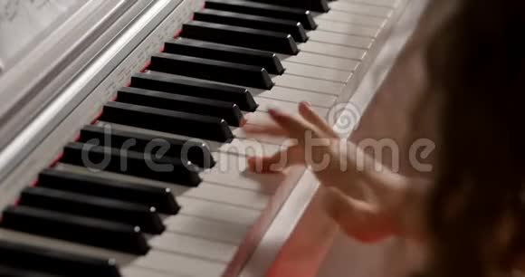 小女孩或儿童专业钢琴家在美丽的白色钢琴上播放古典音乐圣诞假期视频的预览图