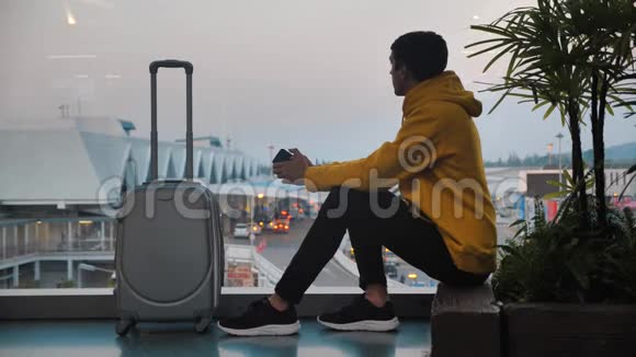 带着行李在机场候机楼等候登机的年轻人坐在窗边视频的预览图