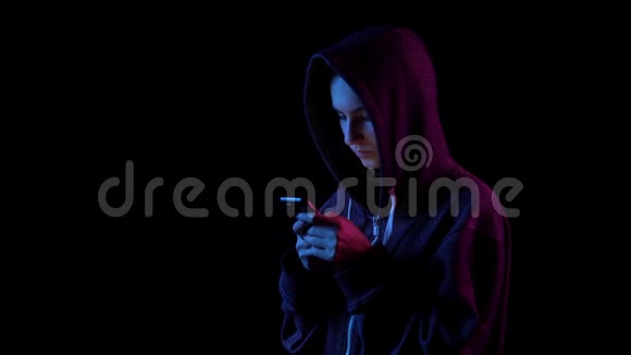 一个戴着兜帽手里拿着电话的年轻女子黑客通过电话攻击蓝色和红色的光落在视频的预览图