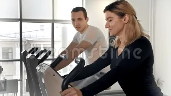 活泼的男人和女人在运动自行车上训练他们的腿互相交谈视频的预览图