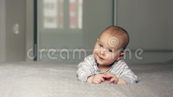 可爱的宝宝躺在床上看着镜头微笑视频的预览图
