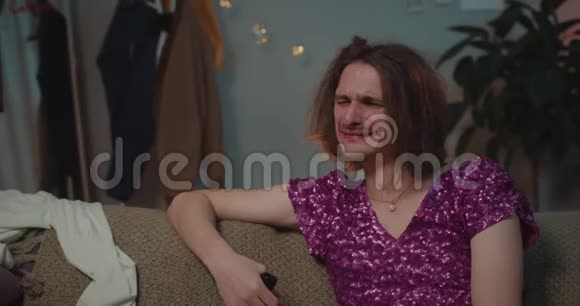 一个醉醺醺的变性人坐在沙发上拿着酒瓶男人分手后感到孤独视频的预览图