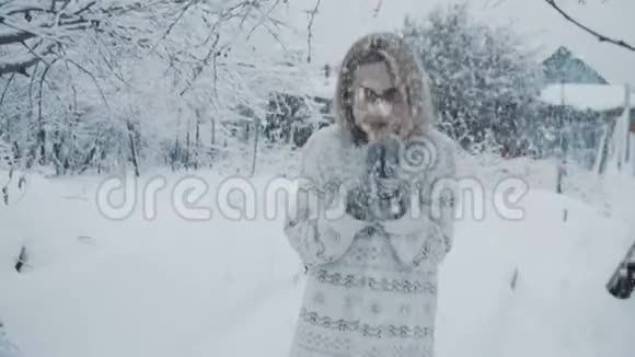 戴着眼镜穿着毛衣戴着手套的女孩站在冬天降雪下的街道上视频的预览图