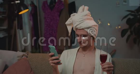 使用智能手机和饮酒在家中关闭轻松的反式男人年轻的变性人在视频的预览图