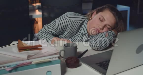 精疲力竭的女商人躺在乱七八糟的桌子上面前放着打开的笔记本电脑劳累的女孩在工作时睡着了视频的预览图