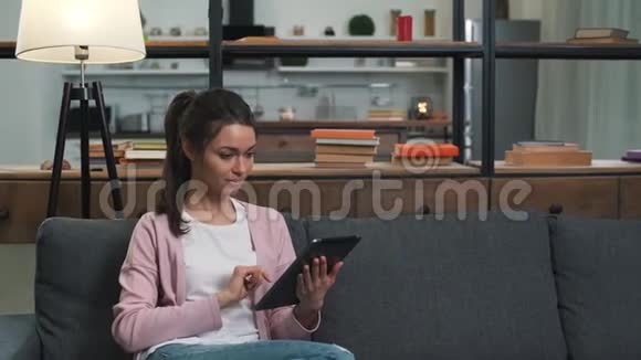 女孩坐在沙发上用平板电脑视频的预览图