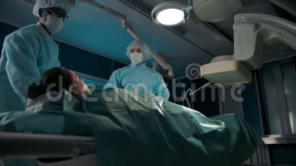 手术室的两位同事在一台X光机下搬了一张沙发里面有一位女性病人视频的预览图