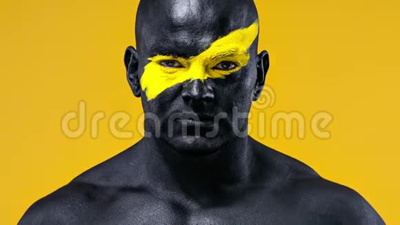 男子体育迷庆祝球队胜利健美运动员脸上有黄色的艺术和黑色的身体油漆五彩缤纷视频的预览图