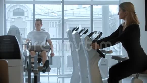 现代健身房年轻男女训练白色现代健身房大全景镜视频的预览图