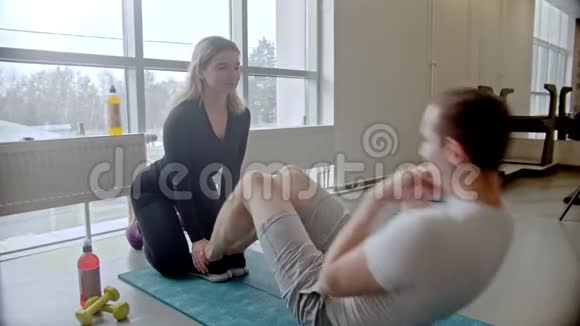 现代健身房男人和女人在健身房健身男人抽他的腹肌视频的预览图