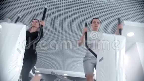 穿着运动服的男人和女人在白色的现代健身房里骑运动自行车他们的腿视频的预览图